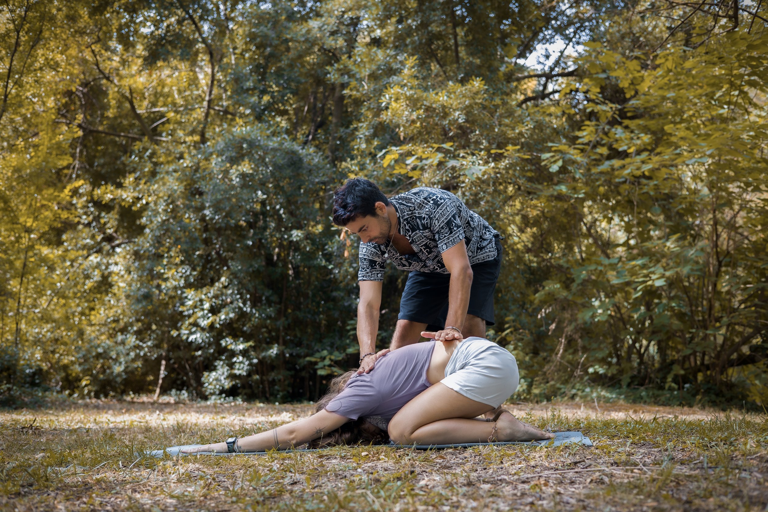 Une personne pratiquant la réanimation cardio-respiratoire sur une autre personne à l'extérieur dans un environnement forestier.